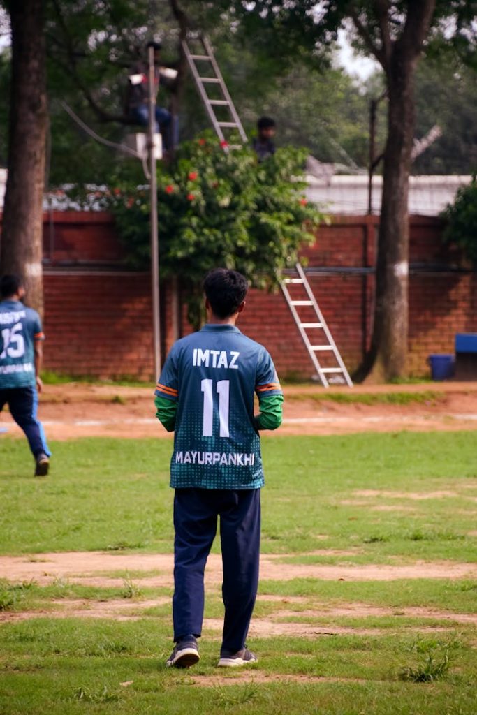 pexels-photo-17628624 A young male cricket player wearing jersey number 11 stands on a grassy field, ready for the game.